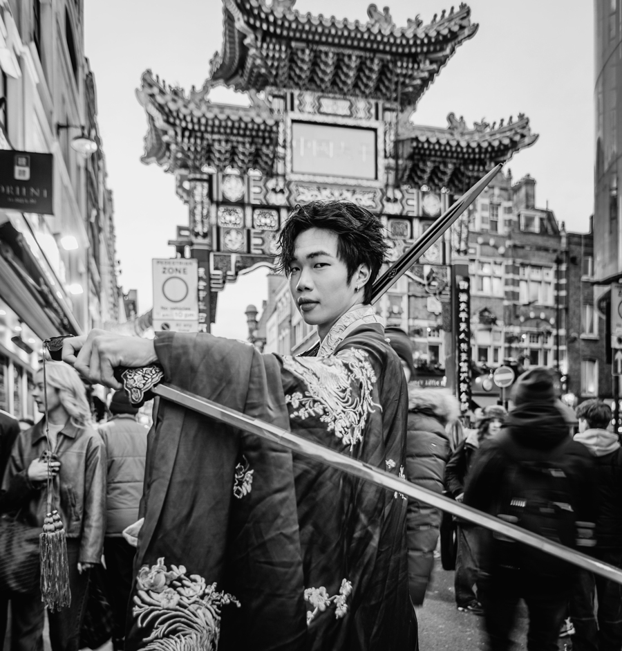 A Chinese man strikes a pose in a traditional hanfu with a two dao (swords) prepares to welcome the lunar new year of the snake in London's Chinatown