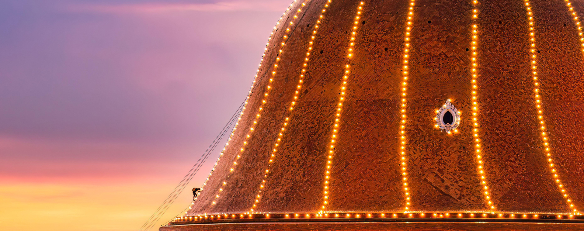 Devout buddhists people climb up to light decoration the grand golden pagoda Phra Pathom Chedi on colorful sunset sky in annual festive at Nakhon Path