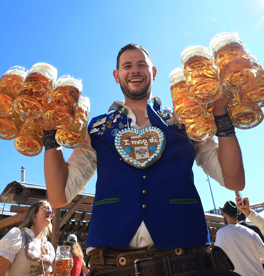 A waiter carries mugs of beer into the Hacker tent on the first day of Oktoberfest on Munich's Theresienwiese, Germany, Saturday, Sept. 20, 2025.